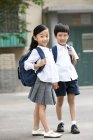 Chinese children with backpacks standing on street — Stock Photo