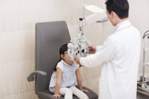 Médico chinês examinando olhos de menina — Fotografia de Stock