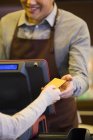 Cliente femenino que paga con tarjeta de crédito en cafetería - foto de stock
