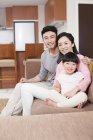 Chinesische Familie ruht auf Sofa und blickt in die Kamera — Stockfoto
