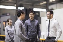 Empresario e ingenieros asiáticos hablando en fábrica - foto de stock