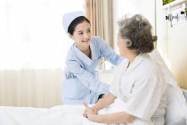 Enfermera china cuidando a una mujer mayor en el hospital — Stock Photo