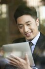 Uomo d'affari cinese che utilizza tablet digitale in caffè — Foto stock