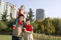 Chinese father carrying daughter on shoulders with mother in park — Stock Photo