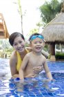 Chino madre e hijo divirtiéndose y mirando en cámara en piscina - foto de stock