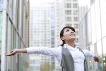 Chinese businesswoman celebrating with arms outstretched in city — Stock Photo