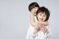 Азіатський брат і сестра обіймаються на сірий фон — стокове фото
