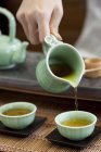Крупный план женских рук, наливающих чай в чайные чашки — стоковое фото