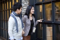 Donna cinese che indica la finestra del negozio mentre passeggia con l'uomo — Foto stock