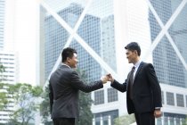 Excited Chinese businessmen celebrating with fist bump on street — Stock Photo
