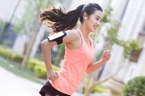 Giovane donna cinese che fa jogging e ascolta musica per strada — Foto stock