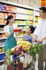 Padres chinos con hijo de compras en el supermercado - foto de stock