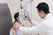 Китайский врач осматривает женские глаза — стоковое фото