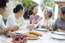 Chinese family talking at dining table in courtyard — Stock Photo