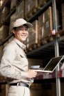 Male Chinese warehouse worker with laptop and scanner — Stock Photo