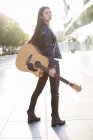 Chinese female guitarist standing with guitar on street — Stock Photo