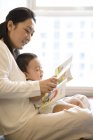 Китайська жінка, що читання з малолітній син — стокове фото