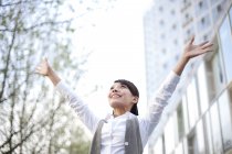 Chinese businesswoman celebrating with arms raised in city — Stock Photo