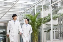 Médicos chinos hablando y caminando en el hospital - foto de stock