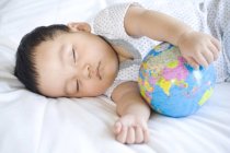Chinese infant sleeping with globe ball — Stock Photo
