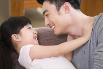 Chinese father playing with daughter on sofa — Stock Photo