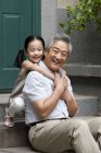 Chinese grandfather and granddaughter embracing on porch — Stock Photo