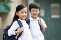Chinese children with backpacks posing on street — Stock Photo
