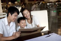 Pais chineses e filho olhando através do menu no restaurante — Fotografia de Stock