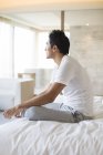 Chinese man sitting on bed — Stock Photo