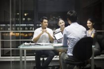 Китайские бизнесмены сидят на встрече с цифровым планшетом — стоковое фото