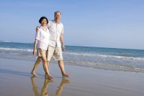 Senior Cinese coppia a piedi lungo mare spiaggia — Foto stock