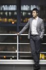 Китайський бізнесмен, спершись на перила в офісі будівлі і дивитися вбік — стокове фото