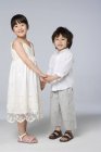 Азиатские дети держатся за руки на сером фоне — стоковое фото
