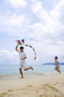 Father and son flying kite at beach — Stock Photo