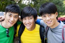 Chinese male backpackers embracing and looking in camera — Stock Photo