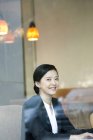 Femme d'affaires chinoise assise dans un café et regardant à la caméra — Photo de stock