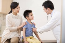 Médecin chinois examinant garçon avec stéthoscope — Photo de stock