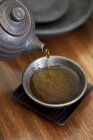 Primer plano del té de hierbas vertiendo en la taza - foto de stock
