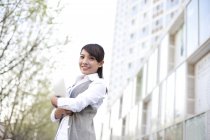 Chinese businesswoman holding digital tablet in city — Stock Photo