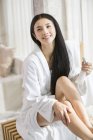 Chinese woman applying moisturizer to skin — Stock Photo
