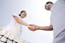Chinese couple shaking hands on tennis court, low angle view — Stock Photo