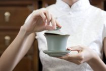 Жінка в традиційному чонгсам тримає чашку китайського чаю — стокове фото
