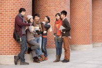 Estudiantes universitarios chinos charlando frente al edificio de la universidad - foto de stock