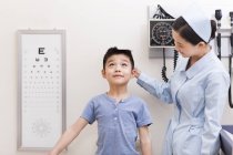 Cinese infermiera misurazione ragazzo in esame stanza — Foto stock