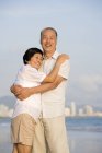 Senior Chinese couple embracing on beach — Stock Photo