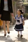 Китайская школьница гуляет с мамой по улице — стоковое фото