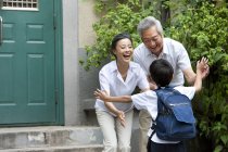 Chinese schoolboy running to grandparents on street — Stock Photo