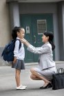 Mãe chinesa ajustando filha escola uniforme na rua — Fotografia de Stock