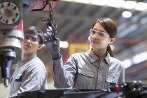 Ingénieurs chinois masculins et féminins travaillant avec une machine en usine — Photo de stock