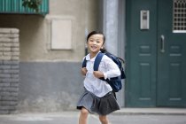 Chinese girl running from school building — Stock Photo
